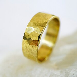 May include: A gold hammered band ring. The ring is thick and has a textured surface.