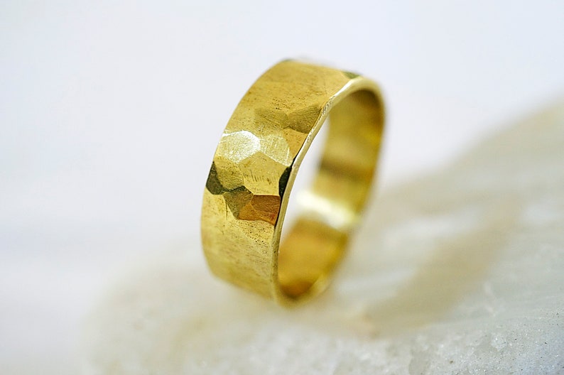 May include: A gold hammered band ring. The ring is thick and has a textured surface.