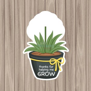 May include: A sticker featuring a potted plant with green leaves and a white cloud-shaped top. The black pot has a yellow bow and the text "thanks for helping me GROW". The background is a wood grain pattern.