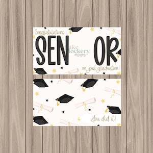 May include: Two graduation cards with a wooden background. The top card reads "Congratulations SENIOR on your graduation!" in black and yellow text. The bottom card has a pattern of graduation caps, diplomas, and stars, with the text "You did it!"