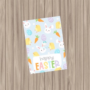 May include: A light blue card with a repeating pattern of white bunnies, yellow chicks, carrots, and pastel Easter eggs. The text "happy easter" is written in rainbow letters on the card.