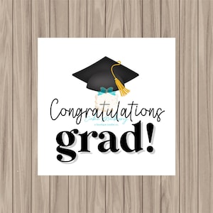 May include: A white background with a black graduation cap and a white cake with blue and yellow decorations. The text "Congratulations grad!" is written in black cursive.