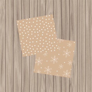 May include: Two sheets of brown wrapping paper with white snowflake and polka dot patterns. The paper is on a woodgrain background.
