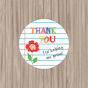 May include: Round sticker with a white background and blue lines. The sticker has a red flower with green leaves and the text "THANK YOU for helping me grow!" in rainbow colors.
