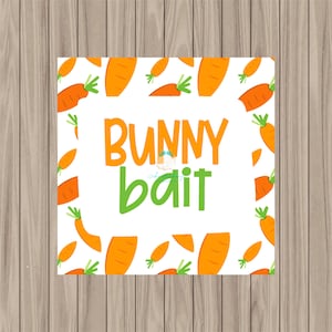 Könnte beinhalten: Quadratische weiße Karte mit orangefarbenen Karotten und den Worten "BUNNY bait" in Orange und Grün. Die Karotten sind um den Rand der Karte angeordnet. Der Hintergrund ist ein hellbraunes Holzmaserung.