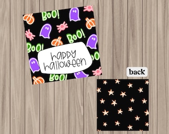 May include: A Halloween card with a black background decorated with ghosts, pumpkins, and the word "Boo!" in green. The card features a white banner with the words "Happy Halloween." The back of the card has a black background with orange stars.