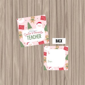 May include: Two pink Christmas gift tags on a wooden surface. One tag says "Santa's Favourite Teacher" with gingerbread men, Santa, and Christmas trees. The second tag has space for "To" and "From".