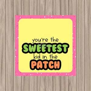 May include: A square card with a yellow center and a pink border adorned with small white hearts. The card features the text "you're the SWEETEST kid in the PATCH" in black, green, and orange.