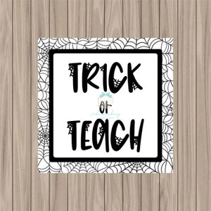 May include: A white sign with a black spiderweb border. The sign says "Trick or Teach" in black text.