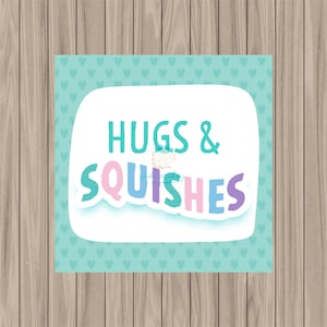May include: A white sign with a blue and green heart pattern background. The sign says "Hugs & Squishes" in colorful letters.