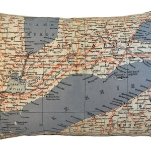 May include: Rectangular pillow featuring a vintage map design of the Great Lakes region, including Ontario, Erie, and Huron. The map is in shades of beige, blue, and orange, with a black border. A decorative accent for home decor.