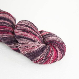 Puede incluir: Un ovillo de hilo en un patrón multicolor de rosa, morado y blanco.