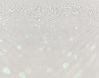 May include: A white surface with a subtle shimmer, creating a soft, sparkling effect. The surface is covered in tiny, iridescent dots that reflect light, creating a delicate and ethereal look.