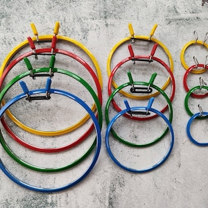 May include: A set of 10 embroidery hoops in various sizes, ranging from small to large. The hoops are made of metal and have a yellow, red, green, and blue finish.