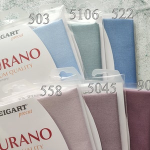 May include: Six fabric swatches in different colors, including light blue, gray, blue, pink, and purple. The swatches are labeled with numbers: 503, 5106, 522, 558, 5045, and 9033. The fabric is labeled "ZWEIGART precut MURANO PREMIUM QUALITY Made in Germany".