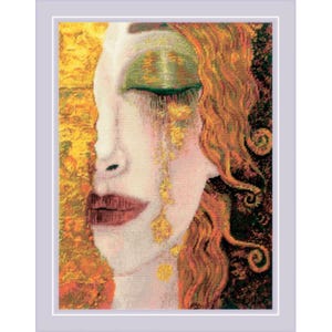 May include: Cross-stitch artwork of a woman's face in profile, with closed green eyes and auburn hair. Gold accents appear as tears and in the background. The artwork is framed in a light purple border.