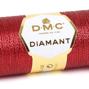 K&ouml;nnte beinhalten: Eine Spule mit DMC Diamant Metallic-Stickgarn in tiefroter Farbe. Die Spule ist mit dem DMC-Logo und dem Text "Diamant" beschriftet.
