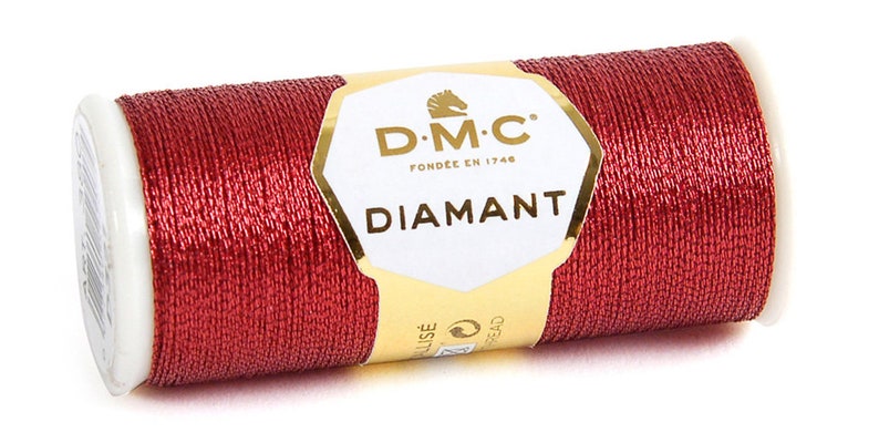 K&ouml;nnte beinhalten: Eine Spule mit DMC Diamant Metallic-Stickgarn in tiefroter Farbe. Die Spule ist mit dem DMC-Logo und dem Text "Diamant" beschriftet.