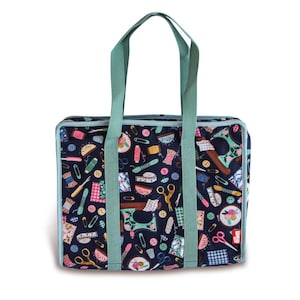 Può includere: Una grande borsa tote blu con una stampa a tema cucito. La borsa ha due lunghe maniglie verdi e un bordo bianco. La stampa presenta macchine da cucire, aghi, filo, bottoni e altri accessori per cucire.