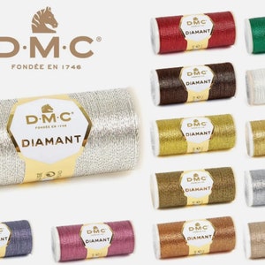 Puede incluir: Una colección de carretes de hilo de bordar DMC Diamant en varios colores metálicos, incluyendo plata, oro, rojo, verde, marrón, y más. Cada carrete presenta el logotipo de DMC y la palabra "Diamant".