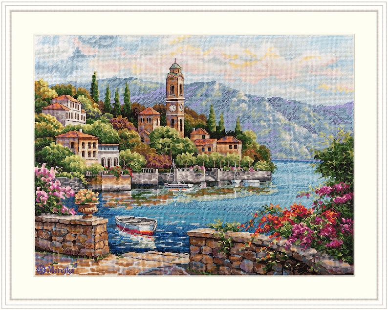 K&ouml;nnte beinhalten: Ein Gem&auml;lde, das ein malerisches italienisches Dorf zeigt, das an einem Hang liegt und einen ruhigen blauen See &uuml;berblickt. Das Dorf verf&uuml;gt &uuml;ber farbenfrohe Geb&auml;ude, einen Glockenturm und &uuml;ppiges Gr&uuml;n. Ein kleines Boot liegt im Vordergrund vor Anker und verst&auml;rkt die ruhige Szene.