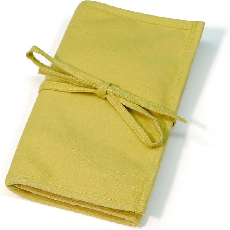 May include: A yellow fabric pouch with a tied ribbon closure. The pouch is folded and appears to be made of a soft, textured material.