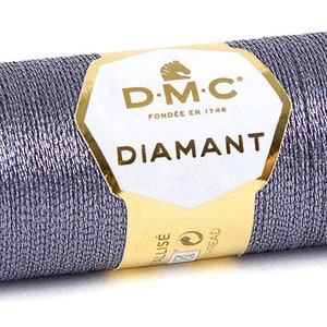 K&ouml;nnte beinhalten: Eine Spule DMC Diamant Metallic-Garn in silbergrauer Farbe. Die Spule ist mit dem DMC-Logo und dem Text "Diamant" beschriftet.