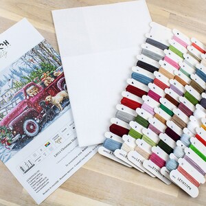 May include: A cross-stitch kit featuring a red truck with a Christmas tree and dogs in the back. The kit includes a white Aida cloth, floss in various colors, and a pattern guide. The kit is labeled "Letistitch Best quality".