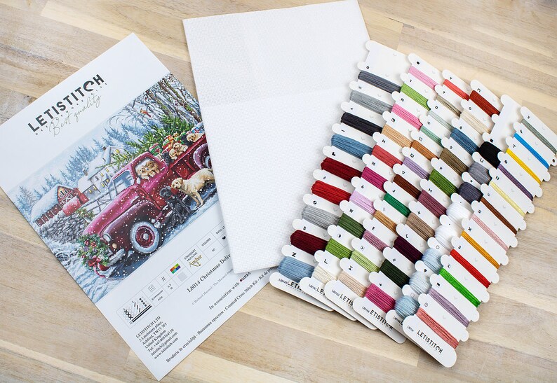 May include: A cross-stitch kit featuring a red truck with a Christmas tree and dogs in the back. The kit includes a white Aida cloth, floss in various colors, and a pattern guide. The kit is labeled "Letistitch Best quality".