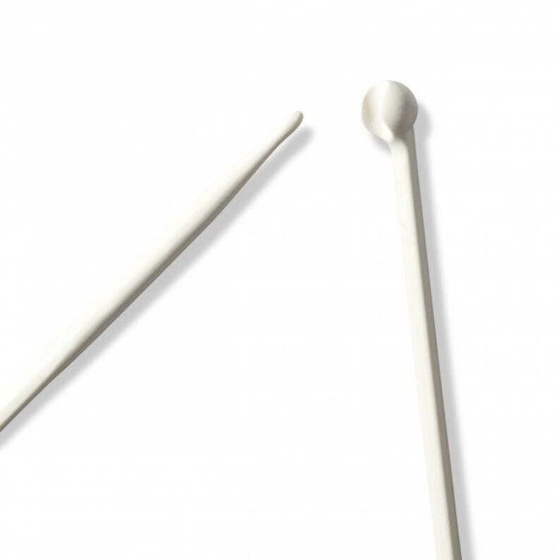 May include: Two white metal stirring sticks, one with a rounded end and one with a pointed end.
