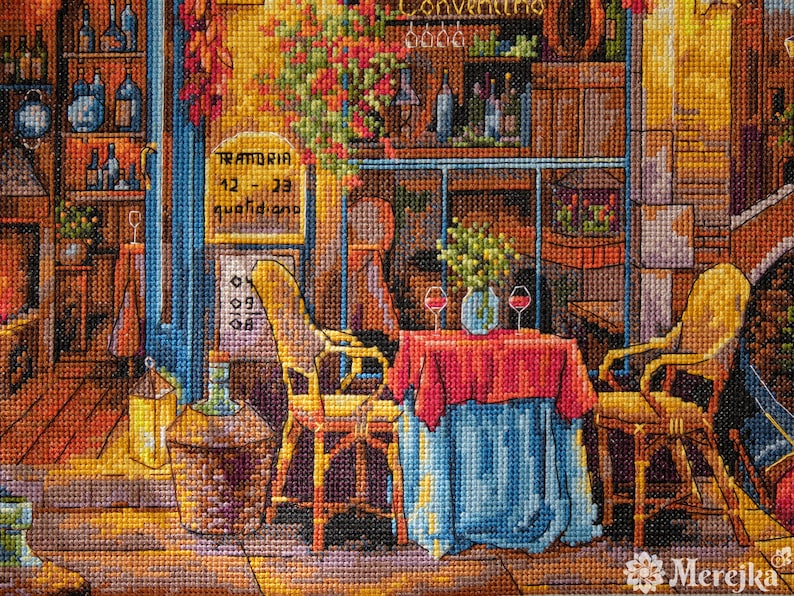 Puede incluir: Una obra de punto de cruz que representa una acogedora escena de restaurante italiano con un mantel rojo y azul, dos sillas y una copa de vino sobre la mesa. El letrero sobre la puerta dice "TRATTORIA 12 - 23 quotidiano".