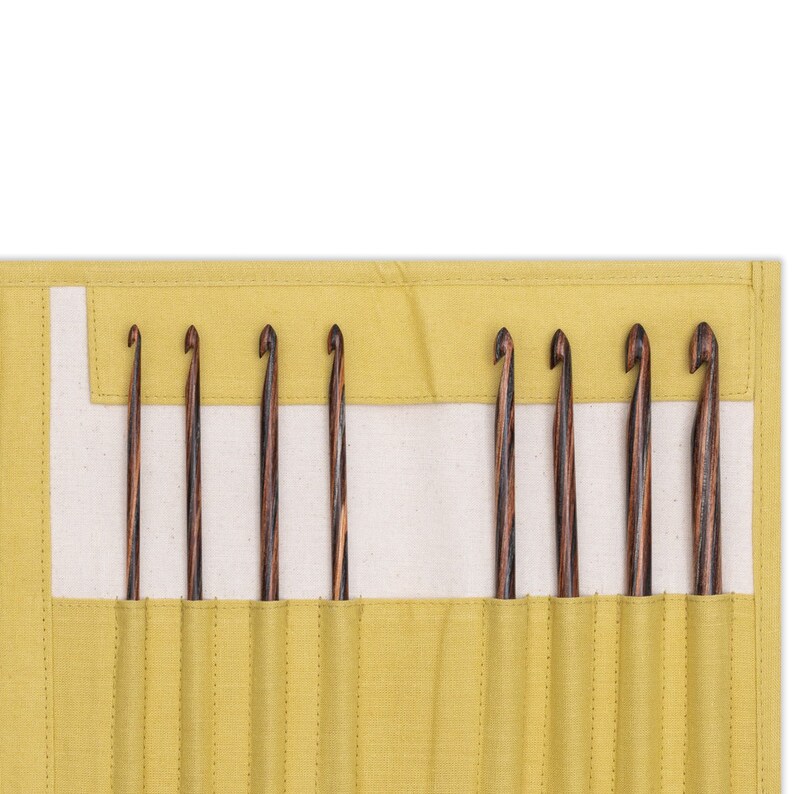 May include: A yellow canvas roll-up case with eight wooden crochet hooks inside. The hooks are arranged in rows and are visible through the clear plastic windows.