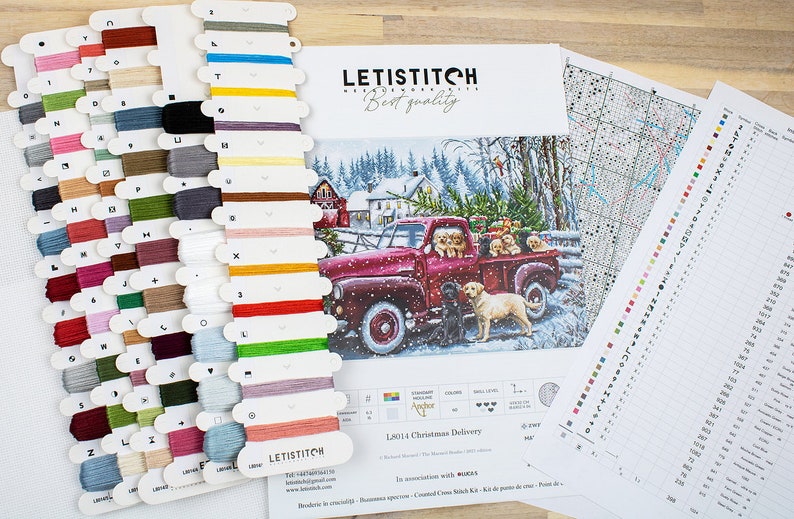 May include: A cross-stitch kit featuring a red truck with a Christmas tree and dogs in the back. The kit includes floss, a pattern, and a needle. The kit is titled "12014 Christmas Delivery".