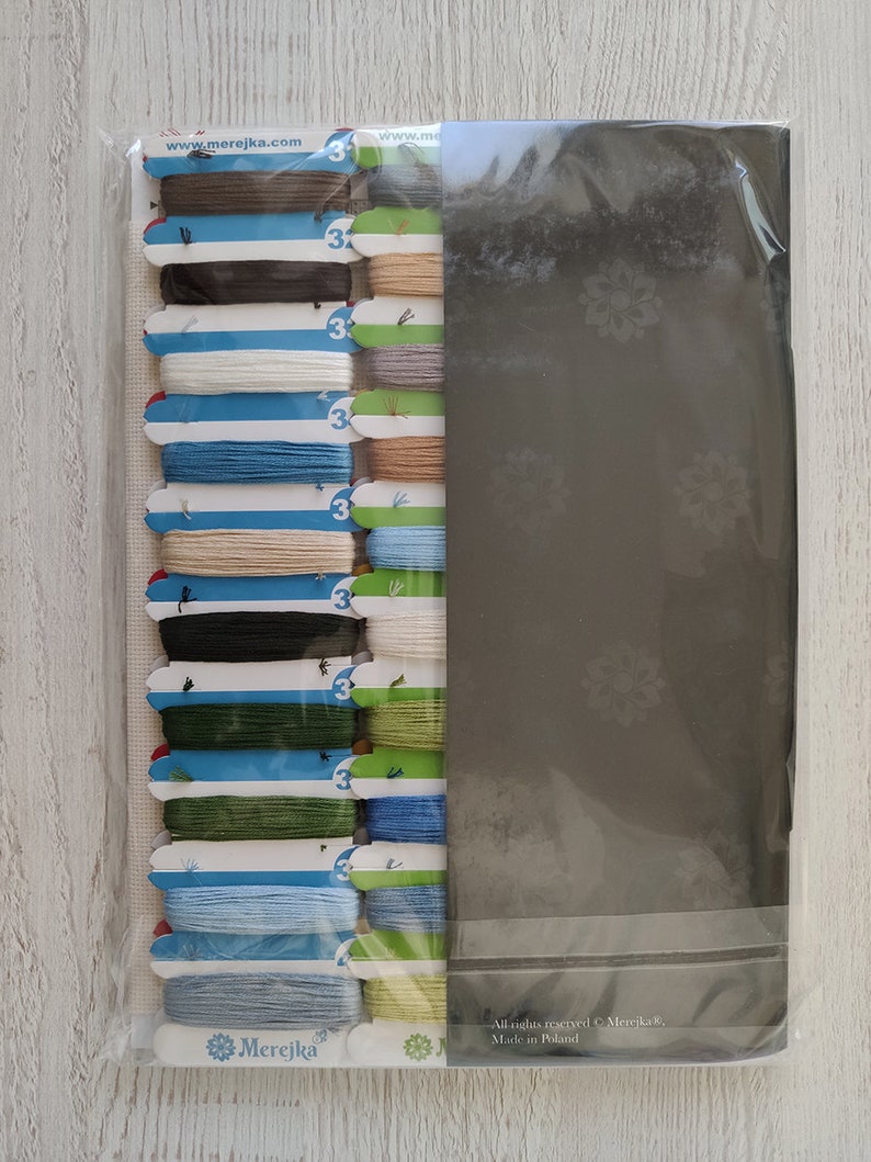 K&ouml;nnte beinhalten: Ein Set mit 16 Stickgarnrollen in verschiedenen Farben, darunter Braun, Blau, Gr&uuml;n und Beige. Die Rollen sind in einer Reihe angeordnet und mit der Nummer "3" gekennzeichnet. Die Rollen sind in einer durchsichtigen Plastikt&uuml;te mit wei&szlig;em Hintergrund verpackt. Die T&uuml;te enth&auml;lt auch eine wei&szlig;e Karte mit dem Text "Merejka" und der Website-Adresse "www.merejka.com". Auf der R&uuml;ckseite der T&uuml;te steht der Text "Alle Rechte vorbehalten &copy; Merejka, Hergestellt in Polen."