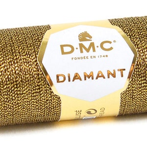 K&ouml;nnte beinhalten: Eine Spule goldfarbener Metallic-Garn mit der Aufschrift "DMC Diamant", dem DMC-Logo und "Fondee en 1746".