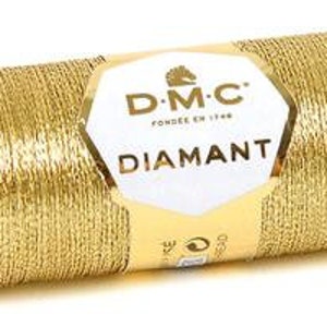 K&ouml;nnte beinhalten: Eine Spule goldfarbener Metallic-Garn mit dem Markenetikett DMC Diamant. Das Etikett zeigt ein Pferdekopf-Logo und den Text "DMC" und "Diamant".
