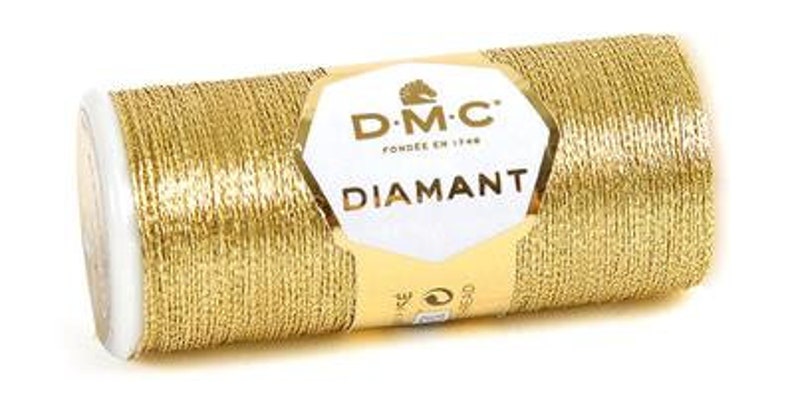 K&ouml;nnte beinhalten: Eine Spule goldfarbener Metallic-Garn mit dem Markenetikett DMC Diamant. Das Etikett zeigt ein Pferdekopf-Logo und den Text "DMC" und "Diamant".
