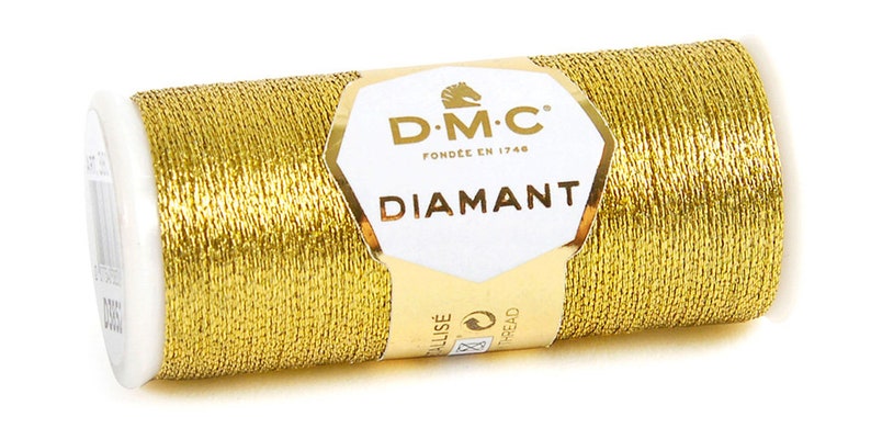 K&ouml;nnte beinhalten: Eine Spule goldfarbener Metallic-Garn mit der Aufschrift "DMC Diamant", dem DMC-Logo und dem Text "Fondee en 1746".