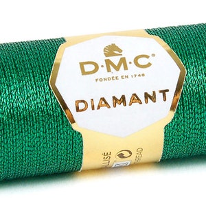 K&ouml;nnte beinhalten: Eine Spule mit gr&uuml;nem Metallic-Garn mit einem goldenen Etikett, auf dem "D.M.C. Fond&eacute;e en 1748 Diamant" steht.