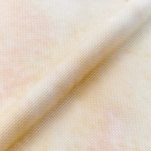 May include: Close-up of a beige fabric with a subtle woven texture. The fabric has a slightly uneven, mottled appearance, with areas of lighter and darker beige.