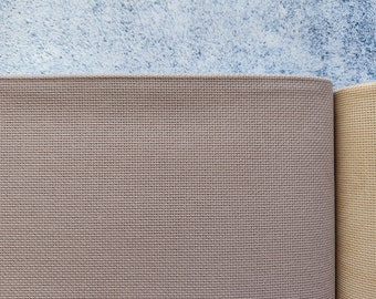 May include: Two pieces of beige fabric with a woven texture. The fabric on the left is a lighter shade of beige than the fabric on the right.