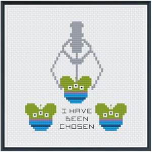 Puede incluir: Patrón de punto de cruz con tres extraterrestres verdes con tres ojos cada uno. Los extraterrestres llevan sombreros azules y morados. El texto "I HAVE BEEN CHOSEN" está debajo de los extraterrestres.