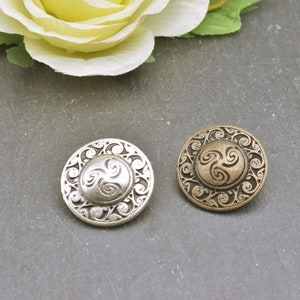 May include: Two decorative buttons with a Celtic knot design. One button is silver and the other is bronze.