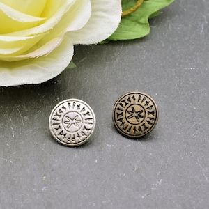 Peut inclure: Deux boutons ronds en métal avec un motif circulaire de runes et une croix au centre. Un bouton est argenté et l'autre est bronze.