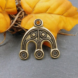 Peut inclure: Pendentif en métal doré avec un motif décoratif composé d'une série de cercles et de points. Le pendentif est en forme d'arche avec trois sections arrondies en bas.