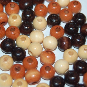 May include: A collection of wooden beads in various colors, including brown, black, cream, and beige. The beads are round and have a smooth finish.