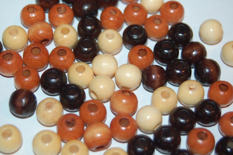 May include: A collection of wooden beads in various colors, including brown, black, cream, and beige. The beads are round and have a smooth finish.