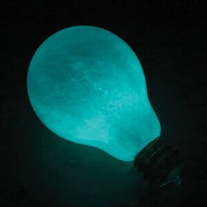 May include: A teal blue light bulb shaped like the moon with a standard light bulb base.
