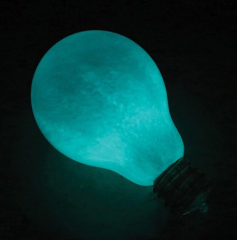 May include: A teal blue light bulb shaped like the moon with a standard light bulb base.