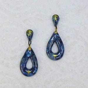 May include: A pair of blue teardrop-shaped earrings with gold accents. The earrings have a small hole in the center of the teardrop.